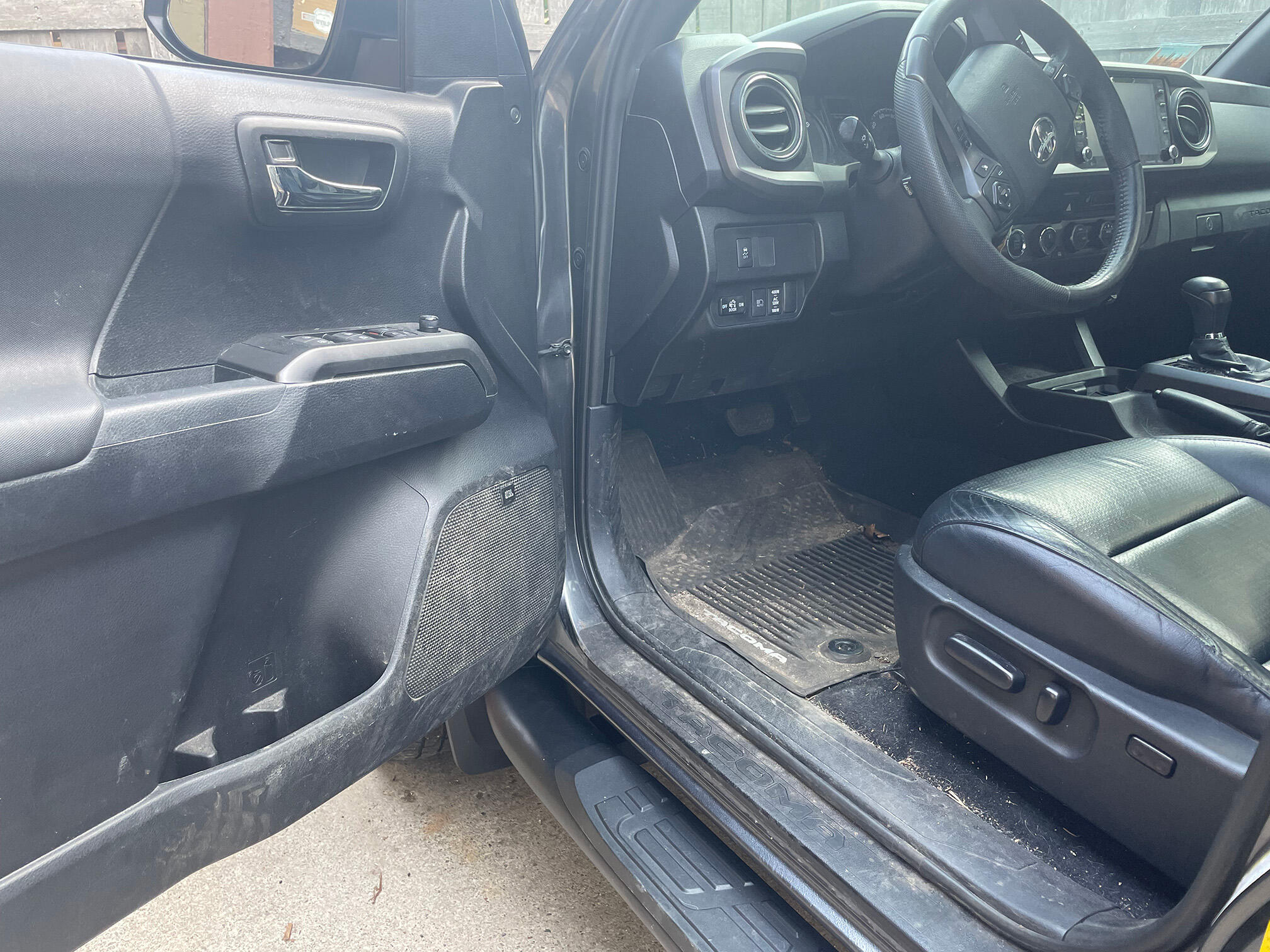 Interior of a car before detailing — muddy floor mats and door, dusty dash in a Toyota Tacoma